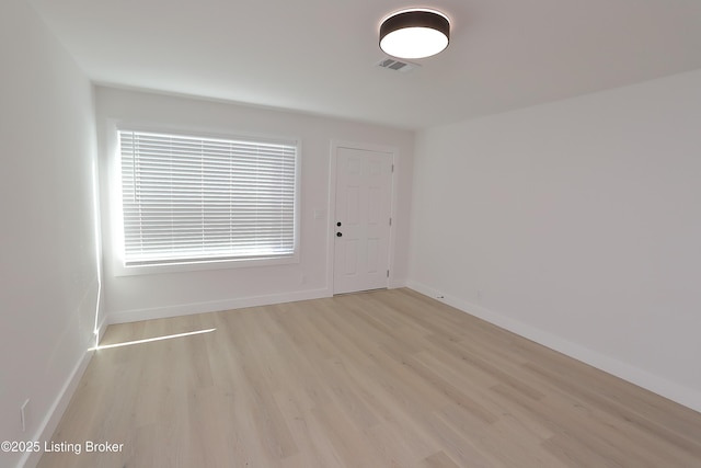 empty room with visible vents, light wood-style flooring, and baseboards