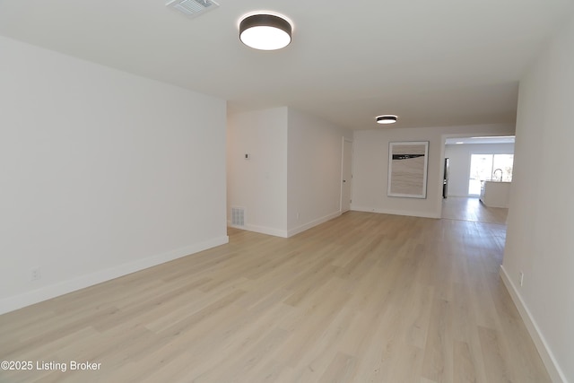 unfurnished room with light wood-style flooring, visible vents, and baseboards