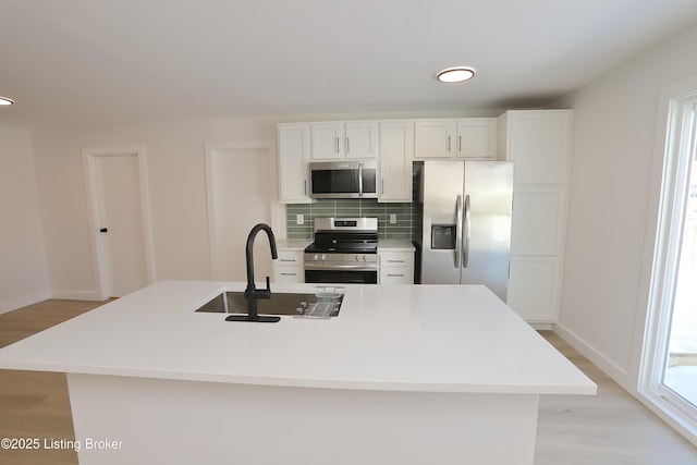 kitchen with appliances with stainless steel finishes, light countertops, white cabinetry, and a sink