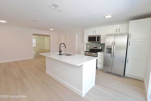 kitchen featuring visible vents, an island with sink, stainless steel appliances, light countertops, and a sink