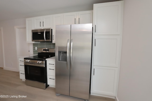 kitchen featuring stainless steel appliances, light countertops, backsplash, and white cabinetry