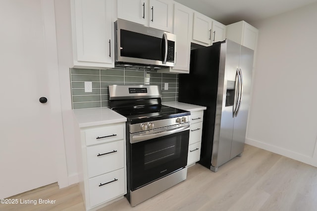 kitchen with decorative backsplash, stainless steel appliances, light countertops, light wood-style floors, and white cabinetry