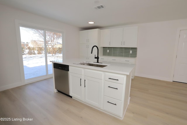 kitchen with a center island with sink, white cabinets, a sink, light countertops, and stainless steel dishwasher