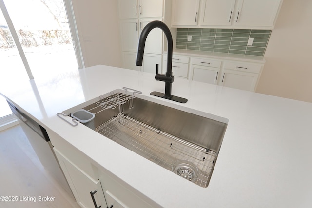 room details featuring light countertops, a sink, backsplash, and white cabinetry