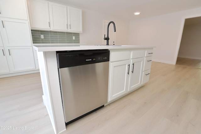 kitchen with dishwasher, an island with sink, light countertops, light wood-style floors, and white cabinetry