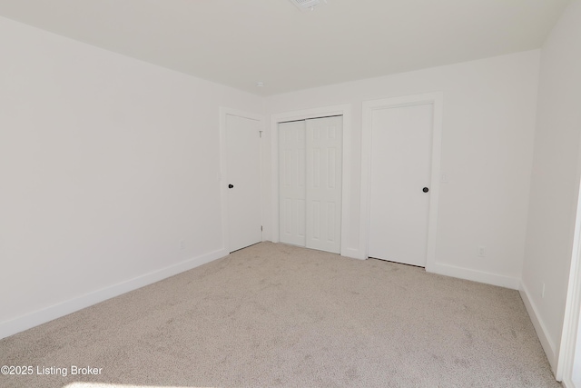 unfurnished bedroom featuring baseboards, two closets, and light colored carpet