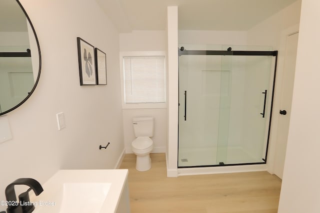 bathroom with a stall shower, baseboards, toilet, wood finished floors, and vanity