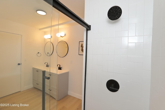 full bathroom featuring tiled shower, wood finished floors, and baseboards