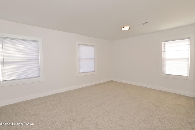 carpeted spare room with visible vents and baseboards