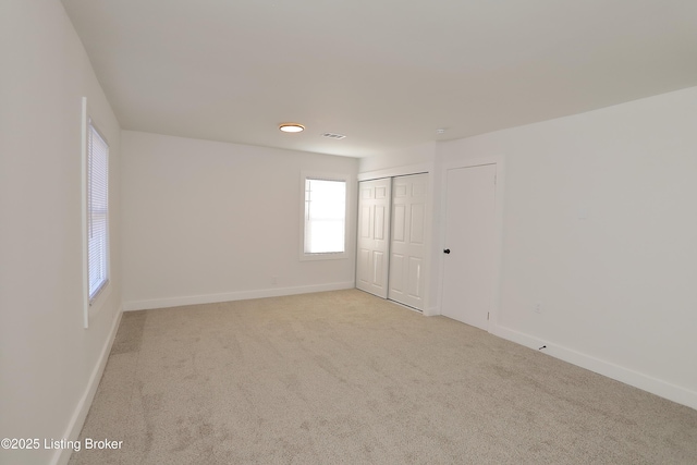 empty room featuring baseboards, visible vents, and light colored carpet