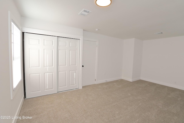 unfurnished bedroom featuring multiple windows, visible vents, and light colored carpet