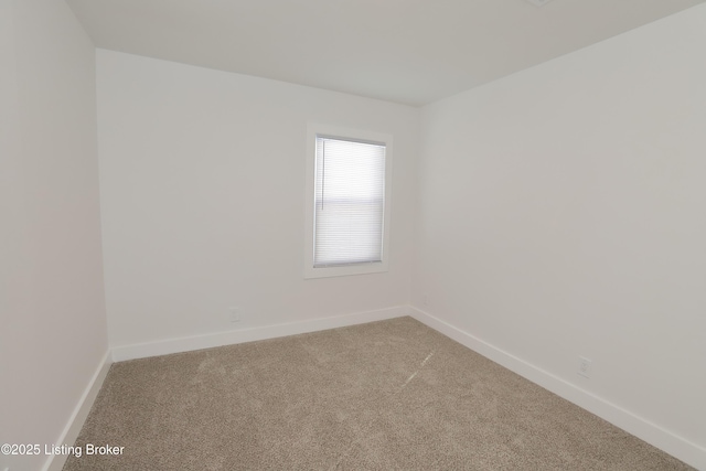 carpeted spare room featuring baseboards