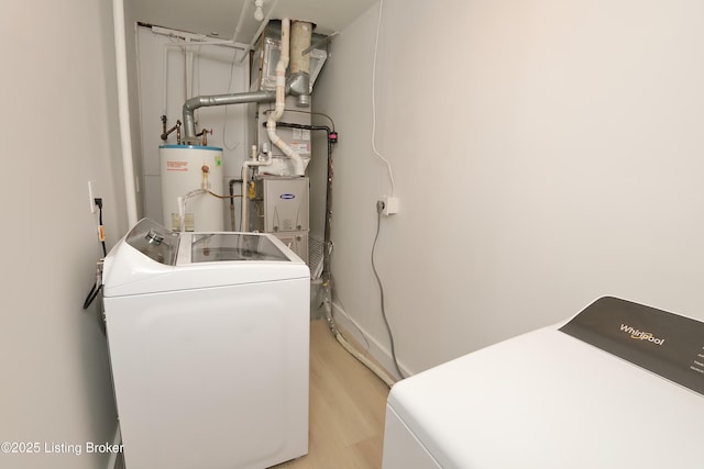 washroom with light wood-type flooring, washer and dryer, laundry area, and water heater