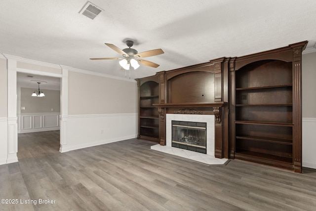 unfurnished living room with a textured ceiling, a tiled fireplace, wood finished floors, and visible vents