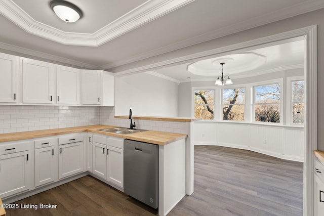 kitchen with a raised ceiling, dishwasher, wood counters, hanging light fixtures, and white cabinetry