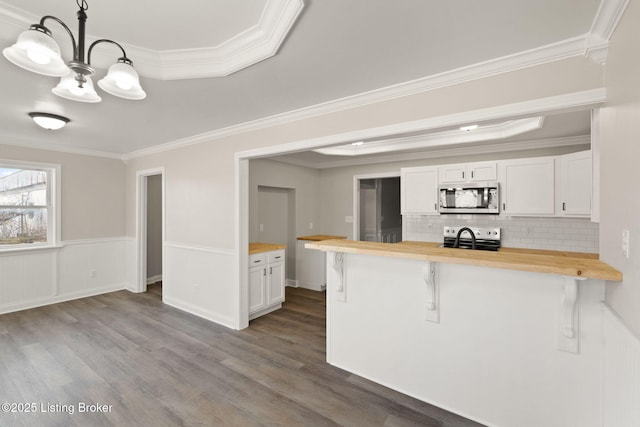 kitchen featuring wood counters, a kitchen breakfast bar, white cabinets, hanging light fixtures, and appliances with stainless steel finishes