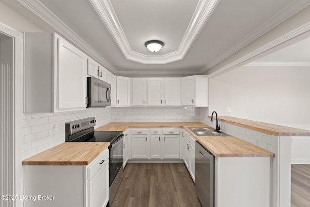 kitchen featuring stainless steel appliances, butcher block countertops, a sink, and white cabinets