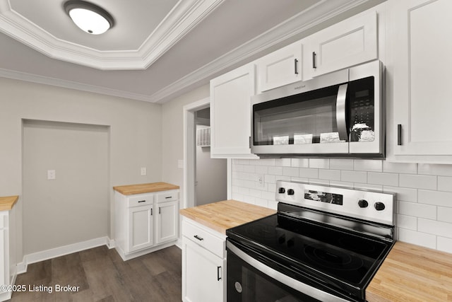 kitchen featuring butcher block countertops, white cabinetry, appliances with stainless steel finishes, a raised ceiling, and crown molding