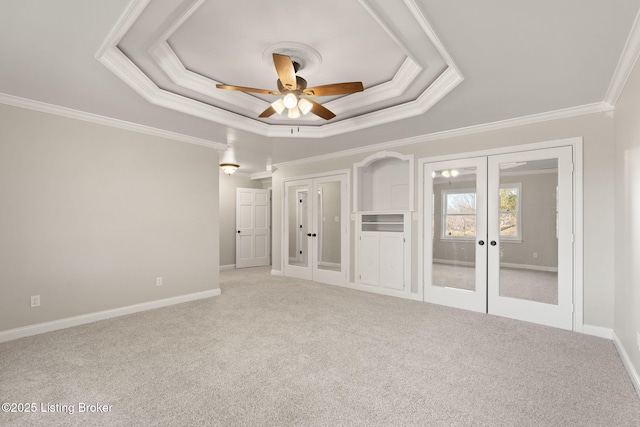 interior space featuring a ceiling fan, baseboards, ornamental molding, french doors, and a raised ceiling