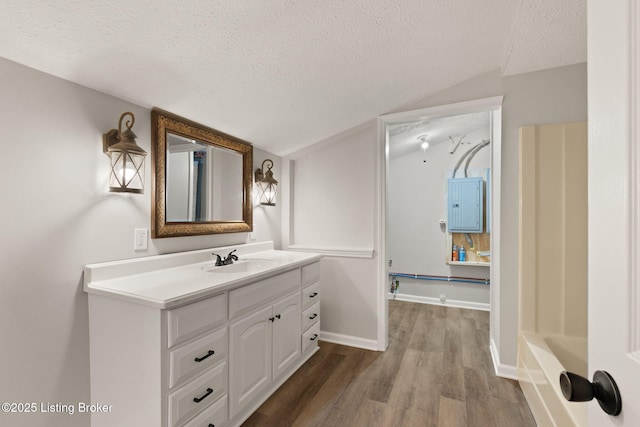 bathroom with a textured ceiling, wood finished floors, vanity, and baseboards