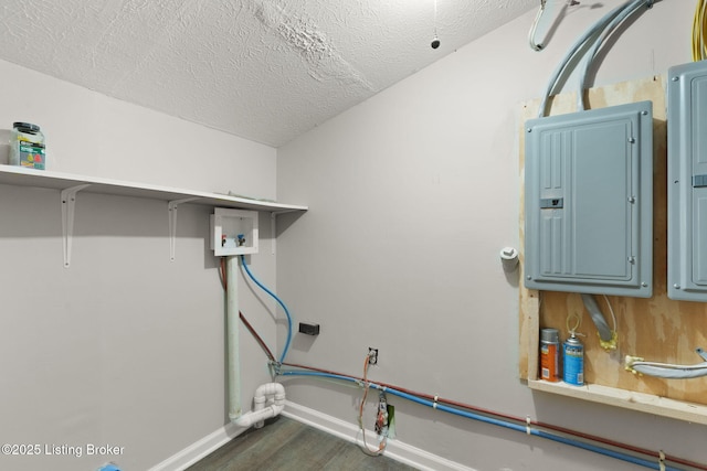 washroom featuring laundry area, electric panel, baseboards, dark wood-style floors, and a textured ceiling