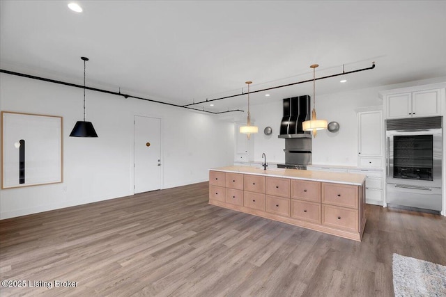 kitchen with extractor fan, white cabinets, light countertops, an island with sink, and pendant lighting