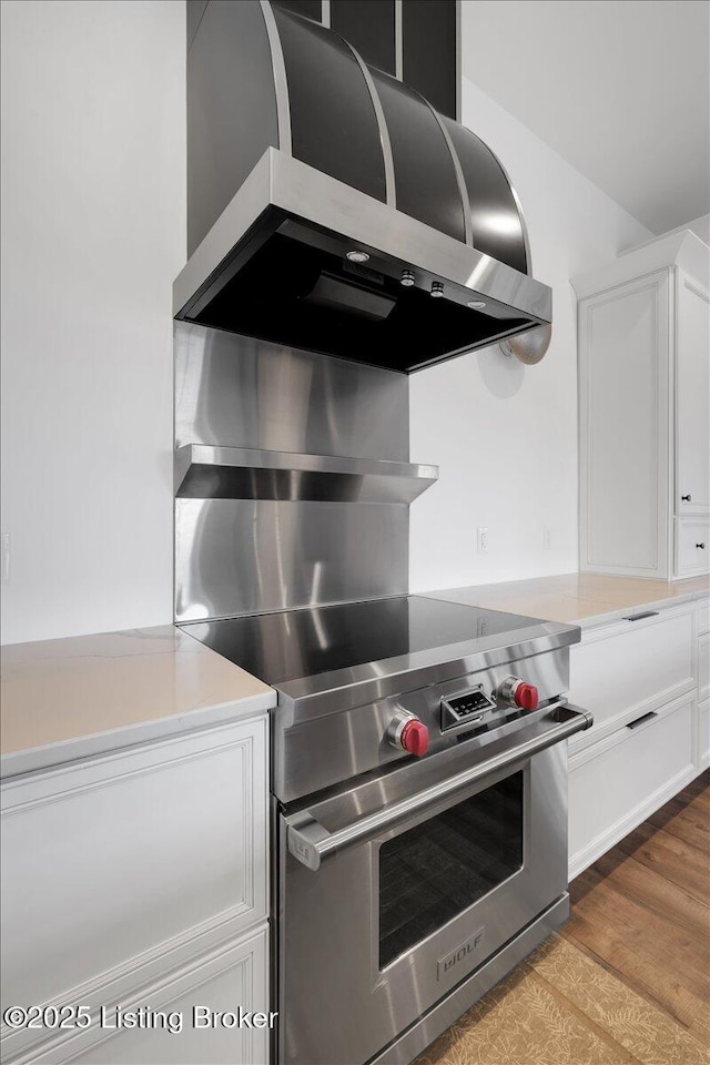 kitchen featuring light wood-style floors, wall chimney exhaust hood, white cabinets, and light countertops