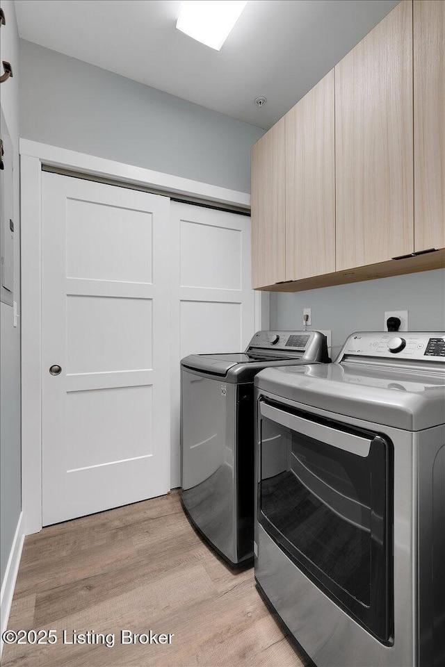 laundry area featuring cabinet space, light wood-style floors, and washing machine and clothes dryer