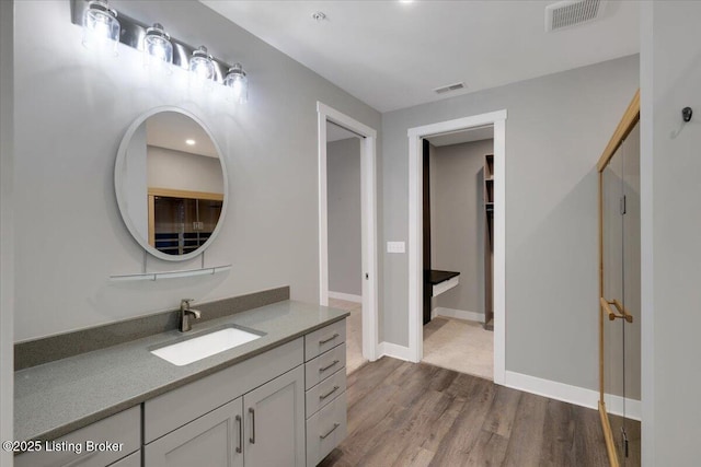 bathroom with baseboards, visible vents, wood finished floors, and vanity