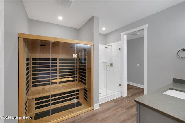 bathroom with visible vents, a sauna, wood finished floors, vanity, and a shower stall