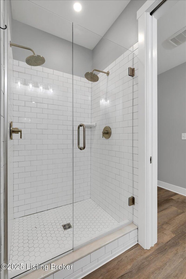 full bath with a stall shower, wood finished floors, visible vents, and baseboards