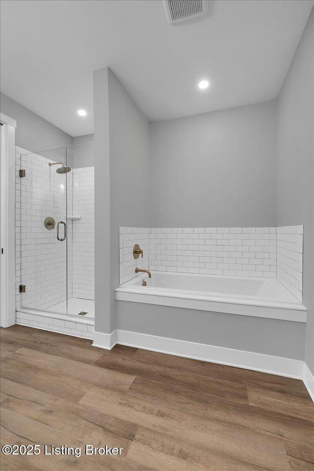 bathroom with baseboards, visible vents, wood finished floors, a garden tub, and a shower stall