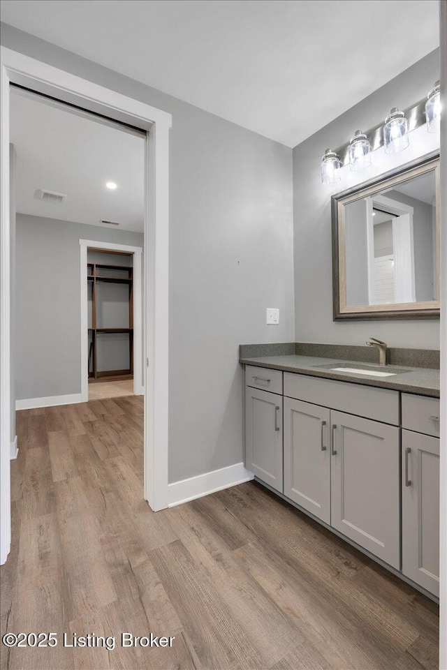 bathroom with vanity, wood finished floors, visible vents, and baseboards