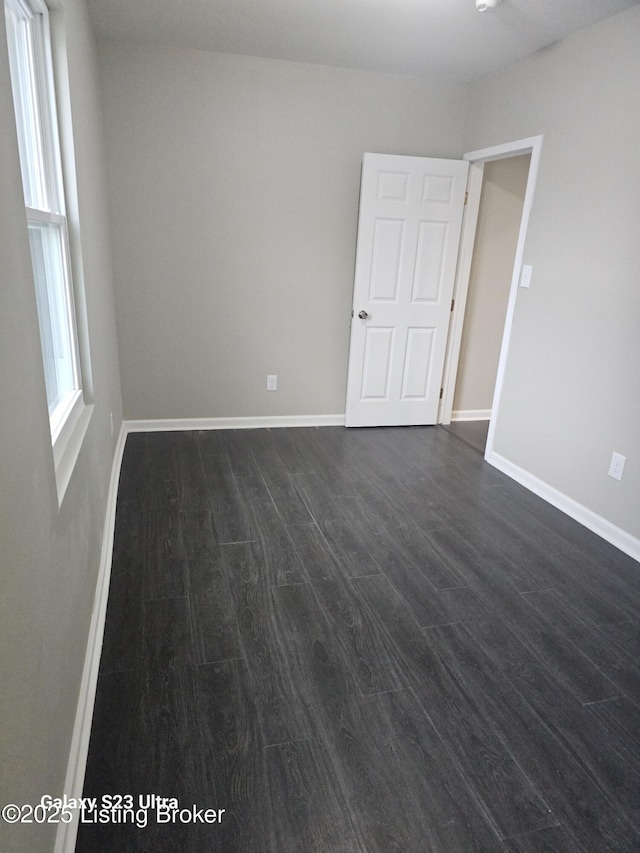 unfurnished room featuring dark wood-type flooring and baseboards