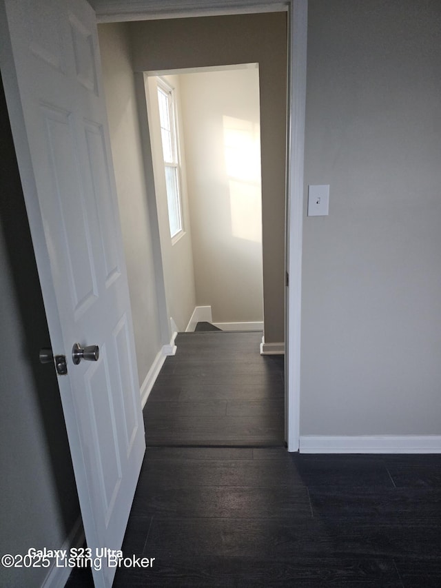 corridor with dark wood-style flooring and baseboards