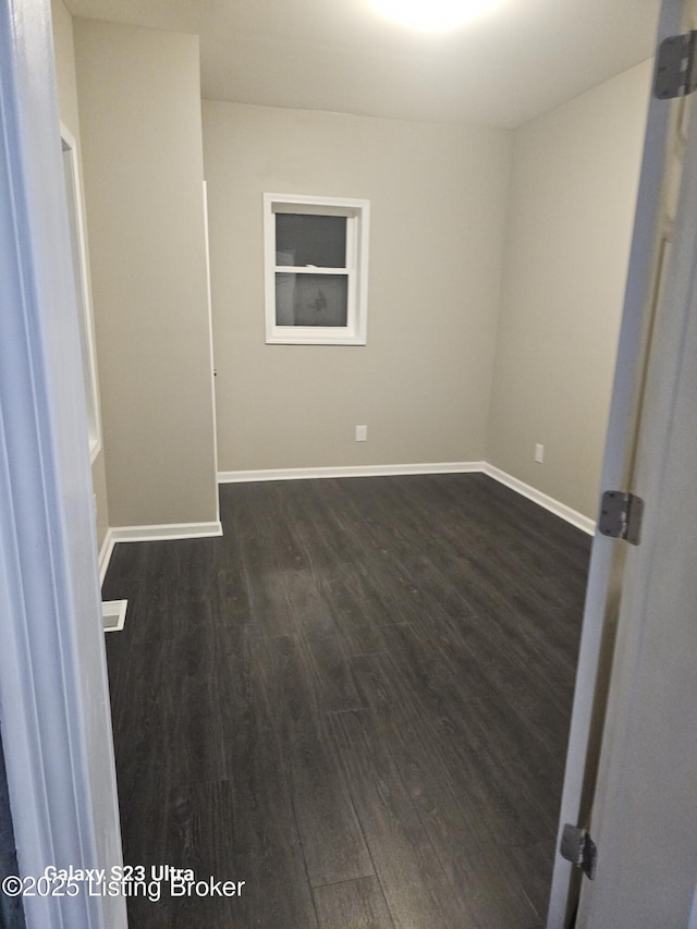 unfurnished room with baseboards and dark wood-style flooring