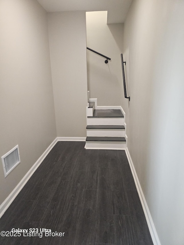 interior space featuring dark wood-style flooring, visible vents, baseboards, and stairs