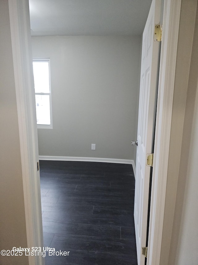 empty room with dark wood-type flooring and baseboards