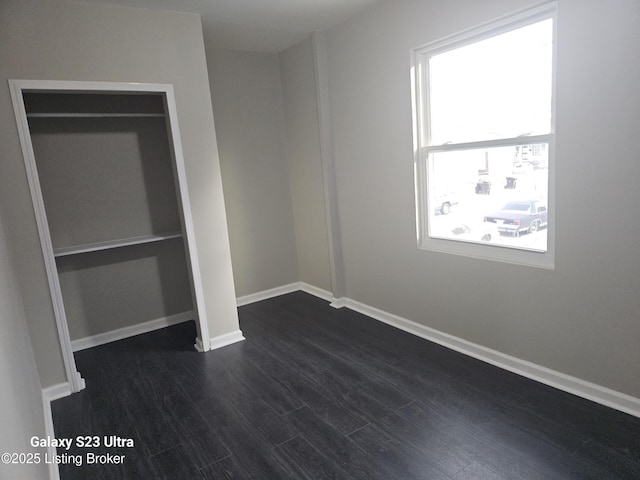 unfurnished bedroom with dark wood-type flooring and baseboards