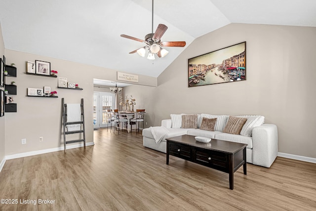 living area featuring ceiling fan with notable chandelier, baseboards, wood finished floors, and lofted ceiling