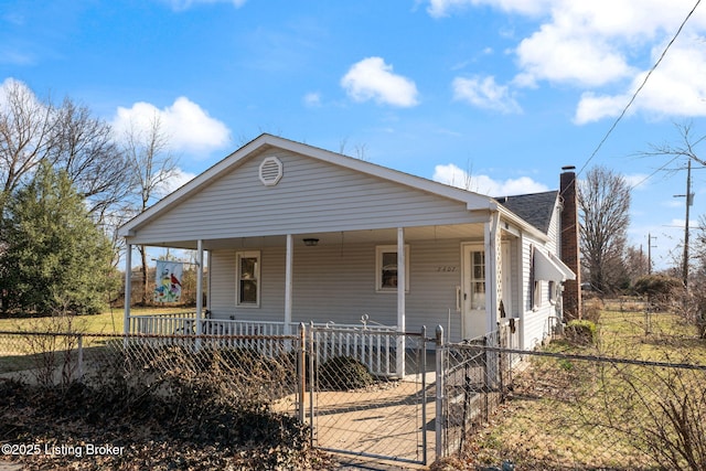 view of front of home with a fenced front yard, a porch, a chimney, and a shingled roof