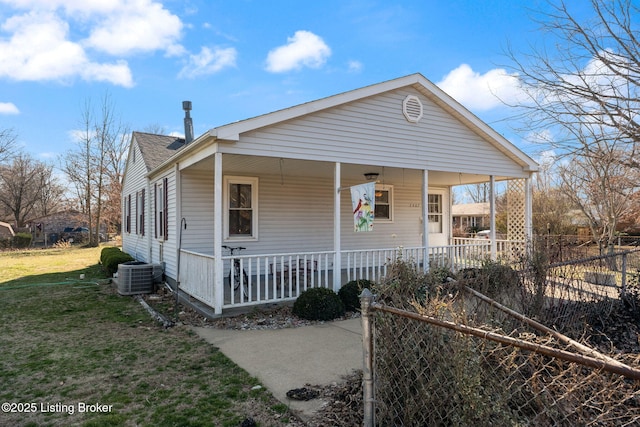 view of front of house featuring central air condition unit, a front lawn, fence, roof with shingles, and covered porch