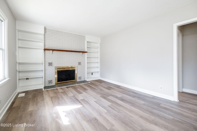 unfurnished living room with wood finished floors, built in features, a fireplace, and baseboards