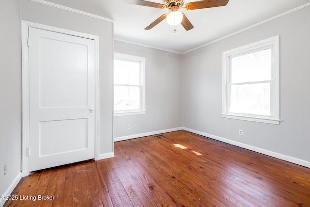 empty room featuring visible vents, baseboards, ceiling fan, hardwood / wood-style flooring, and crown molding