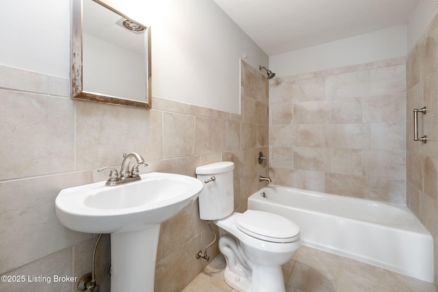 bathroom with tub / shower combination, toilet, tile walls, and tile patterned floors