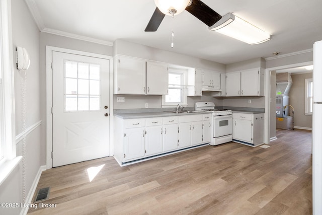 kitchen with white gas stove, white cabinetry, light wood-type flooring, and a sink