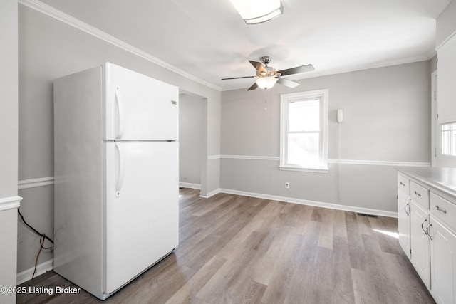 kitchen with light wood finished floors, white cabinetry, freestanding refrigerator, and a wealth of natural light