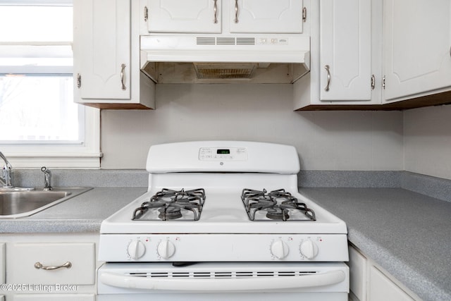 kitchen with backsplash, under cabinet range hood, white gas range oven, white cabinets, and a sink