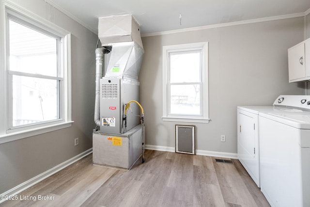 laundry room with washing machine and clothes dryer, crown molding, baseboards, light wood-type flooring, and cabinet space