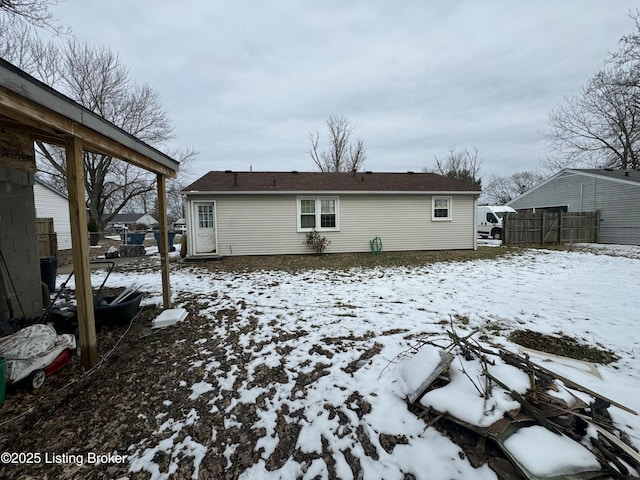 snow covered back of property with fence